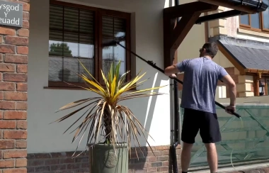 Technician using a water-fed pole to clean a conservatory roof and upper windows