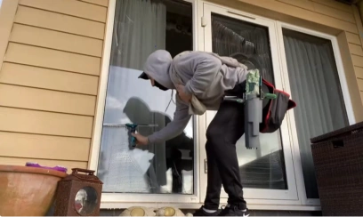 Technician squeegee-cleaning patio door glass by hand