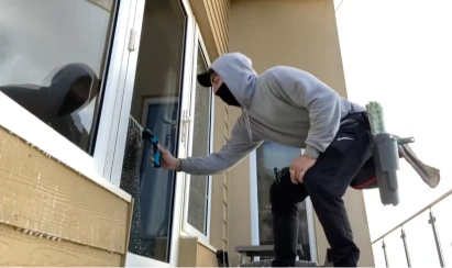 Technician cleaning a balcony window by hand with a squeegee